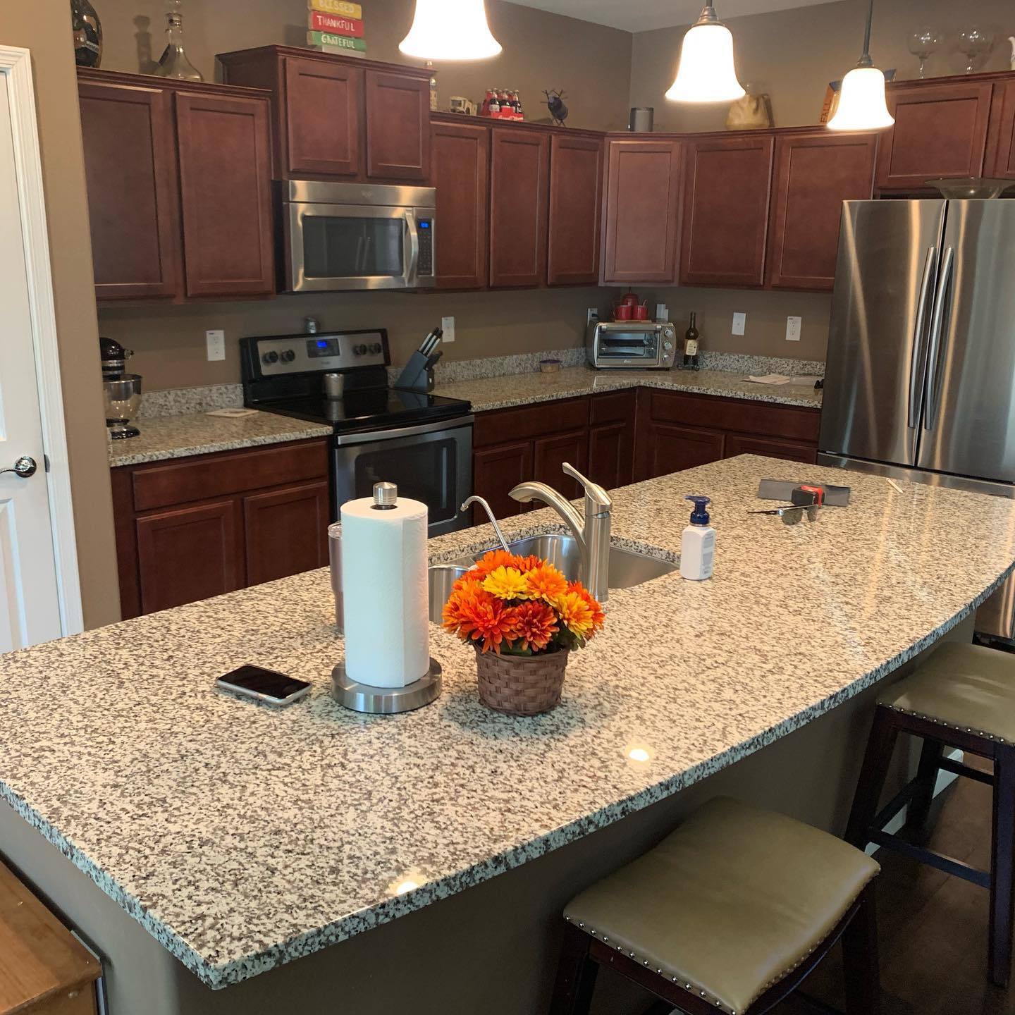 VM Stoneworks — Speckled granite island countertop with cherry cabinetry